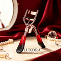 Red and black eyelash curler with rose gold-tone frame